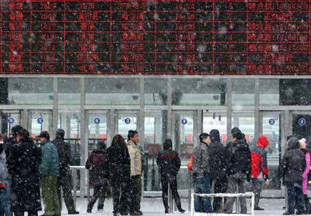 Travelers wait in front of the ticket office in snow at Harbin Railway Station on Sunday. [Photo/Xinhua]