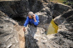 An elder peasant squats beside a disappearing pond due to severe drought in the Bouyei and Miao autonomous prefecture, southwest China's Guizhou province, February 23, 2010. [Xinhua photo]