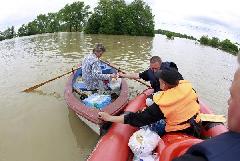 An emergency worker gives food suplies to a man on the boat at the flooded village of Juliszew close to Plock in Central Poland May 24, 2010. [Xinhua/Reuters]