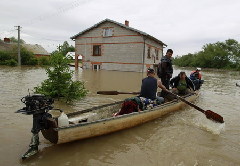 Locals in a boat float past a house in the flooded village of Juliszew May 24, 2010.[China Daily/Agencies]