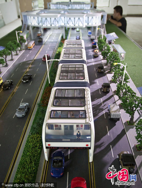 A visitor looks at a scale model of &apos;straddle bus&apos;. The &apos;straddle bus&apos;, invented by Shenzhen Huashi Future Parking Equipment Co. Ltd., on display at an office showroom in Beijing, Friday, Sept. 3, 2010. [CFP]