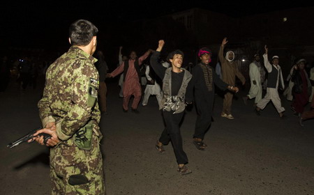 An Afghan policeman watches over protestors shouting anti US slogans as they celebrate after learning that S. pastor Terry Jones dropped his plans to burn copies of the Quran, in Herat, western Afghanistan September 12, 2010. [Agencies] 