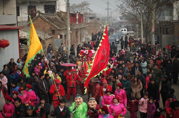 Local residents walk next a traditional Chinese wedding procession in Dong&apos;an at the central province of Henan, February 9, 2011. [China Daily/Agencies]