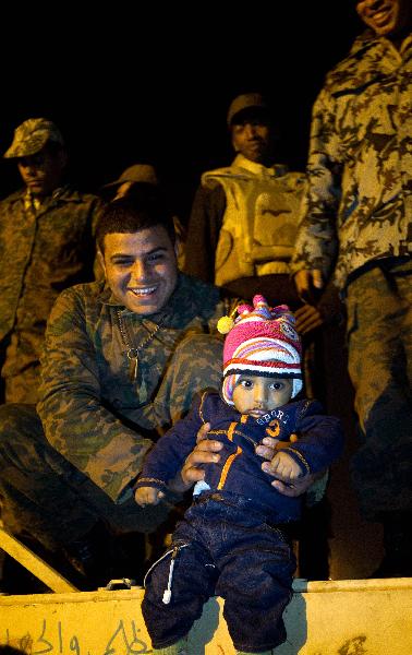 A child poses for photos in front of a tank as people celebrate the resignation of Egyptian President Hosni Mubarak on Tahrir Square in Cairo, Egypt, Feb. 11, 2011. Egypt's President Hosni Mubarak steps down and the military take charge of the country, Egypt's Vice President Omar Suleiman said on Friday afternoon. 