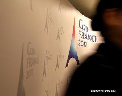 A woman walks past a poster of the G20 meeting of Finance Ministers and Central Bank Governors at the G20 press center in Paris, France, Feb. 18, 2011. The 2-day G20 meeting of Finance Ministers and Central Bank Governors opened here on Friday. 