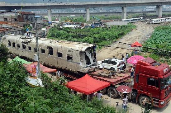 An excavator is used to dismantle a carriage of a derailed train from Saturday's devastating rail crash near the city of Wenzhou in East China's Zhejiang province.