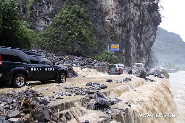 Vehicles trudge on a flooded road in Xingshan County of Yichang City, central China's Hubei Province, Aug. 22, 2011. Rain-triggered mudslides hit the mountainous region in Yichang on Monday, blocking the No. 209 National Highway and leaving hundreds of people stranded. 