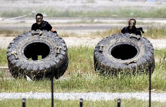 Special policemen push tires which weight more than a hundred kilogram during an anti-terror drill in Shanghai, Sept 14, 2011. [Photo/Xinhua] 