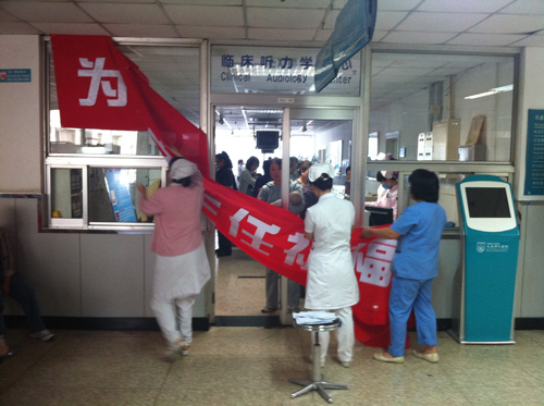 Hospital staff takes down a banner hanging in the otolaryngology department of Beijing Tongren Hospital on Sept. 20, 2011. [By Daniel Xu/China.org.cn]